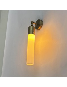 Aged brass wall light with a glowing opal tube, creating a warm and elegant ambient effect. 2